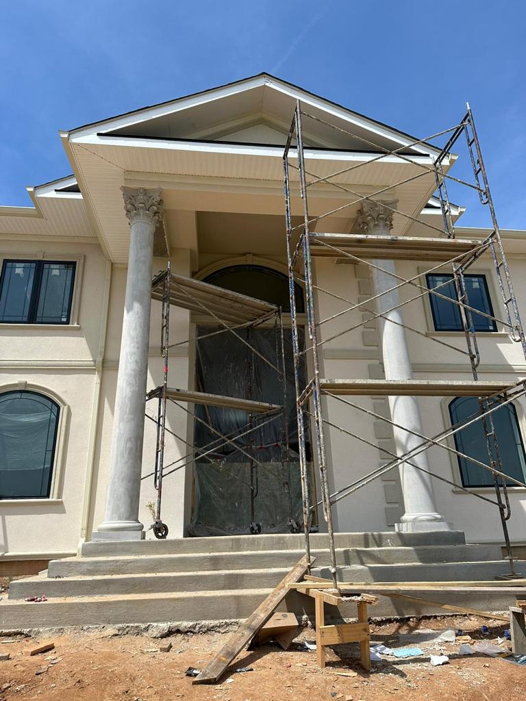 Scaffolding set up in front of a big building with two large columns at the entrance.