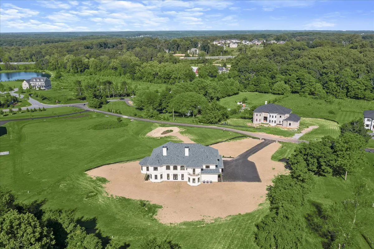 Aerial view of a residential luxury estate, set amidst expansive greenery and neighboring homes.